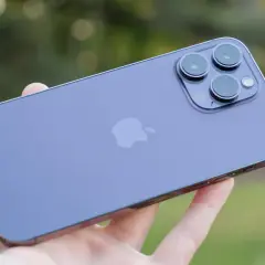 En hand håller en lila iPhone 14 med sin imponerande trippelkamera.