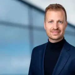 Mats Ståhl står stolt i en mörkblå kavaj och polotröja, med en suddig blå bakgrund.