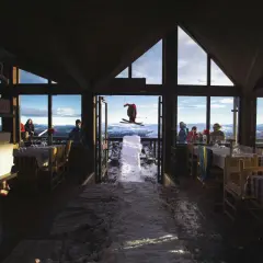 En skidåkare i luften utanför en restaurang med utsikt över fjällen. Kanske en paus för Sophie Odelberg.