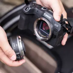 Händer byter objektiv på en Canon EOS R8. Vad betyder RF? Det är objektivfattningen, som på denna kamera är RF-fattning.