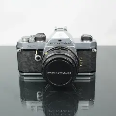 En klassisk Pentax MX-kamera med objektivlock.