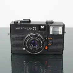 Svart Konica C35 EFP-kamera med blixt och Konica Hexanon-objektiv. Perfekt för att fånga klassiska ögonblick.