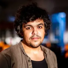 Alexander Mahmoud, en ung man med lockigt mörkt hår och skäggstubb, blickar mot kameran.