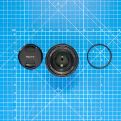 Sony-objektiv med lock och filterring på blått rutmönster. Lär dig vad distorsion betyder för bildkvaliteten.