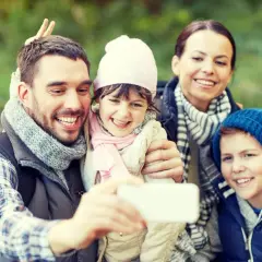 Familjen tar en glad selfie med Samsung i skogen. Pappa gör kaninöron bakom dotterns huvud.