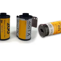 Tre filmrullar: en 35mm färgfilm, en 35mm svartvit film och en 120-film. Dessa visar hur framkallar man bilder från analog film.