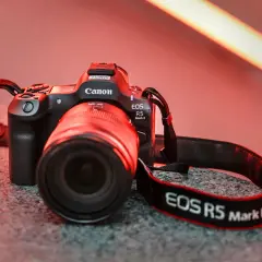 En Canon EOS R5 Mark II med objektiv och rem ligger på en stengrund.