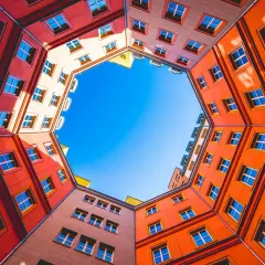 Fasaderna på ett färgglatt hus bildar en cirkel runt en klarblå himmel. Fönstren är många och speglar ljuset. En vacker vy att skapa bild av.