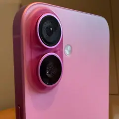 Rosa iPhone med dubbla linser på kameran, bredvid en gammal Macintosh-dator.