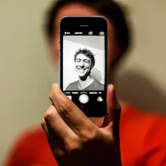 En person tar en selfie med en iPhone. Personen ler brett mot kameran.