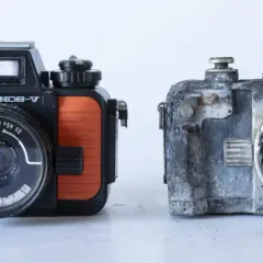 En orange och svart Nikonos V bredvid en sliten, grå kamera.