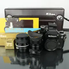 En svart Nikon F2 kamera med objektiv, blixtkopplare och originalförpackningar.