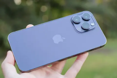 En hand håller en lila iPhone 14 med sin imponerande trippelkamera.