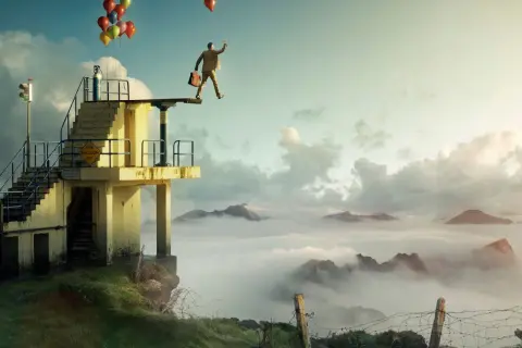 En man med portfölj och ballonger står på en dykplattform över moln. Erik Johansson fotograf.