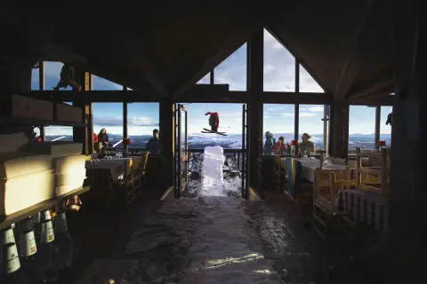 En skidåkare i luften utanför en restaurang med utsikt över fjällen. Kanske en paus för Sophie Odelberg.
