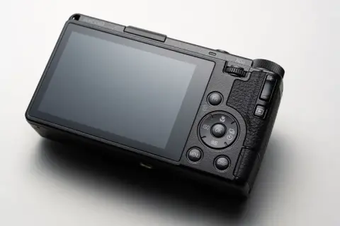 Svart Ricoh GR IV-kamera med stor skärm och knappar för inställningar.