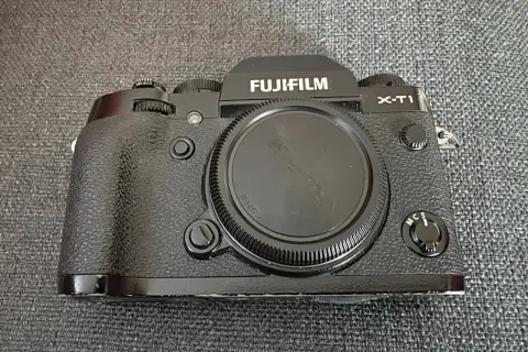 En svart Fujifilm X-T1 kamera ligger på en grå bakgrund.