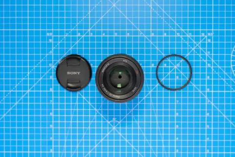 Sony-objektiv med lock och filterring på blått rutmönster. Lär dig vad distorsion betyder för bildkvaliteten.