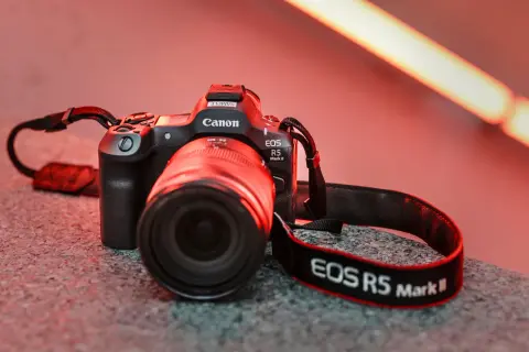 En Canon EOS R5 Mark II med objektiv och rem ligger på en stengrund.
