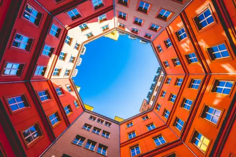 Fasaderna på ett färgglatt hus bildar en cirkel runt en klarblå himmel. Fönstren är många och speglar ljuset. En vacker vy att skapa bild av.