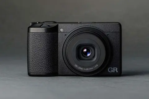 Svart kompaktkamera, en Ricoh GR III X, med texten "GR LENS f=26.1mm 1:2.8" på objektivet.