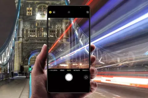 En hand håller en iPhone som fångar ljusspår från bilar vid Tower Bridge. En lång slutartid på iPhone ger en dramatisk effekt.