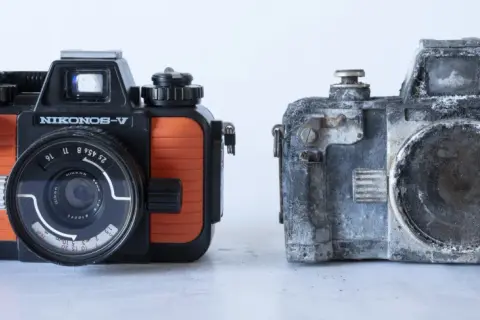 En orange och svart Nikonos V bredvid en sliten, grå kamera.