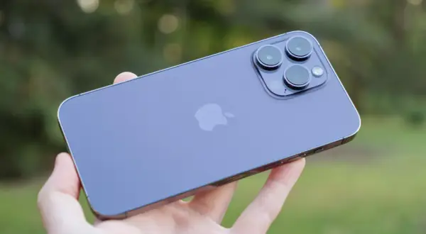 En hand håller en lila iPhone 14 med sin imponerande trippelkamera.