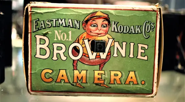En grön låda med en tecknad figur som håller en kamera. Texten "Eastman Kodak Co.'s No.1 Brownie Camera" syns tydligt.
