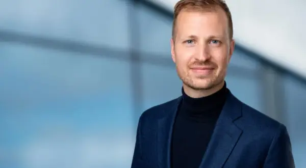 Mats Ståhl står stolt i en mörkblå kavaj och polotröja, med en suddig blå bakgrund.