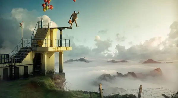 En man med portfölj och ballonger står på en dykplattform över moln. Erik Johansson fotograf.
