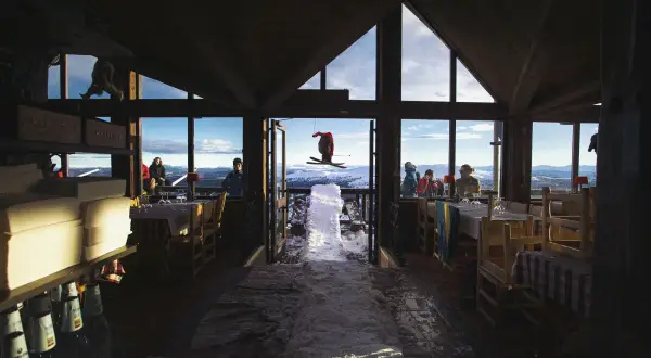 En skidåkare i luften utanför en restaurang med utsikt över fjällen. Kanske en paus för Sophie Odelberg.