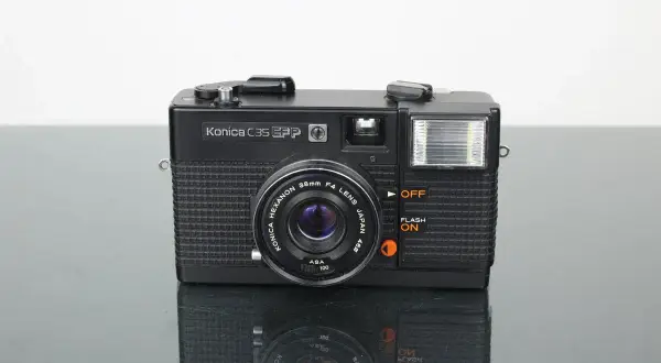 Svart Konica C35 EFP-kamera med blixt och Konica Hexanon-objektiv. Perfekt för att fånga klassiska ögonblick.