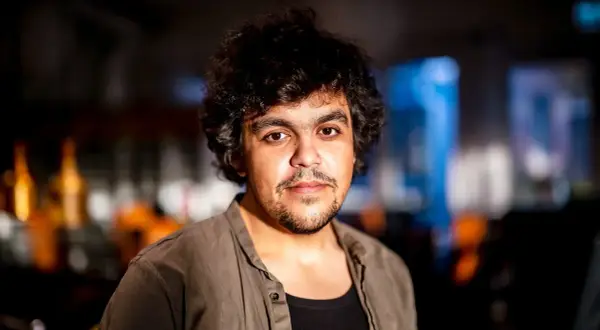Alexander Mahmoud, en ung man med lockigt mörkt hår och skäggstubb, blickar mot kameran.