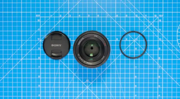 Sony-objektiv med lock och filterring på blått rutmönster. Lär dig vad distorsion betyder för bildkvaliteten.