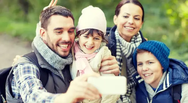 Familjen tar en glad selfie med Samsung i skogen. Pappa gör kaninöron bakom dotterns huvud.