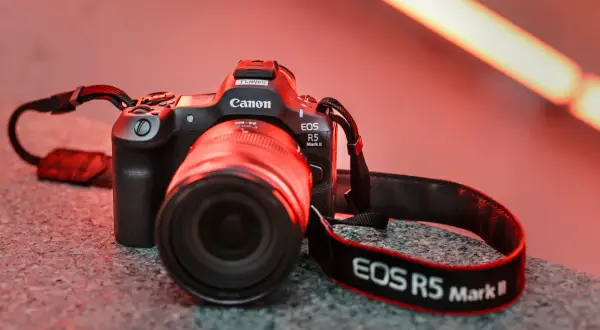 En Canon EOS R5 Mark II med objektiv och rem ligger på en stengrund.