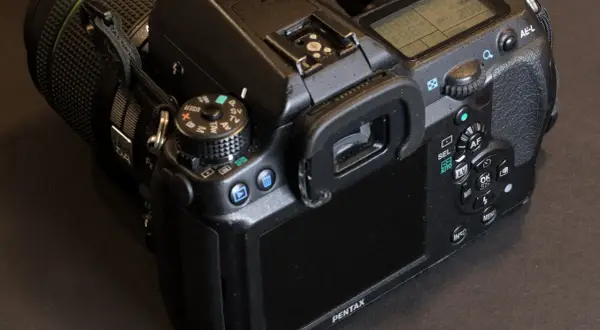 En närbild på en Pentax K5 systemkamera med objektivet på. Knappar och skärm syns tydligt.
