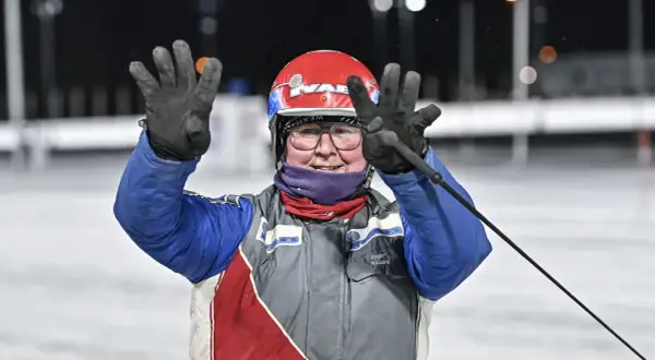 Jenny Rehnman vinkar glatt med båda händerna, klädd i tävlingskläder och hjälm.