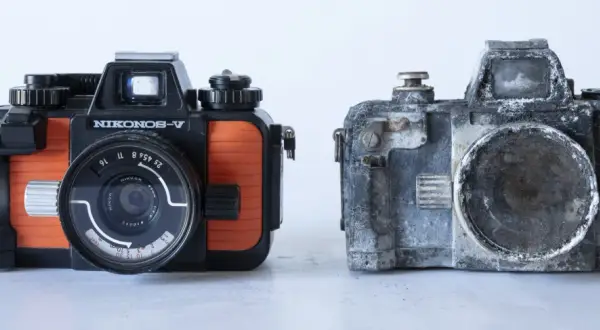 En orange och svart Nikonos V bredvid en sliten, grå kamera.