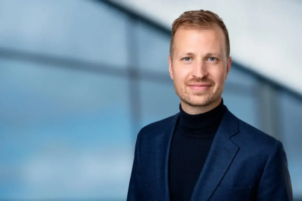 Mats Ståhl står stolt i en mörkblå kavaj och polotröja, med en suddig blå bakgrund.