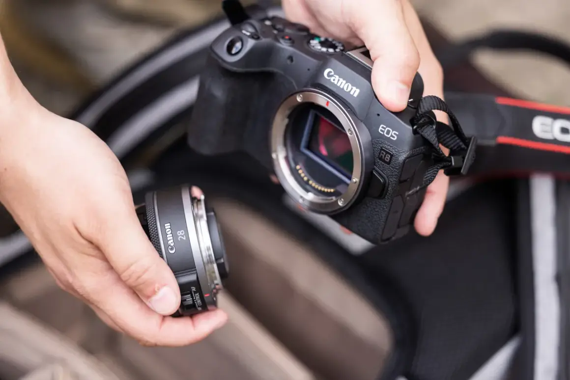 Händer byter objektiv på en Canon EOS R8. Vad betyder RF? Det är objektivfattningen, som på denna kamera är RF-fattning.