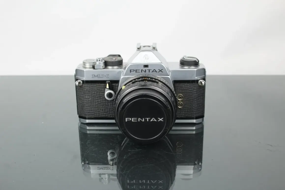 En klassisk Pentax MX-kamera med objektivlock.