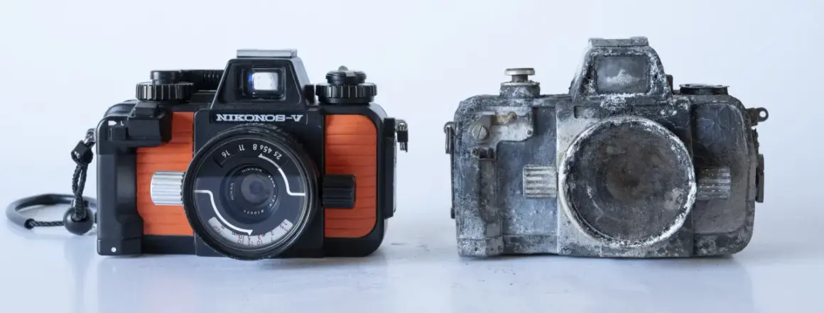 En orange och svart Nikonos V bredvid en sliten, grå kamera.