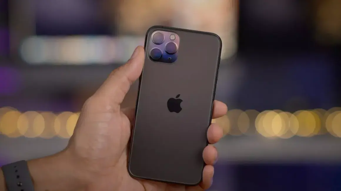 En hand håller en mörk iPhone 11 Pro med sin imponerande trippelkamera.