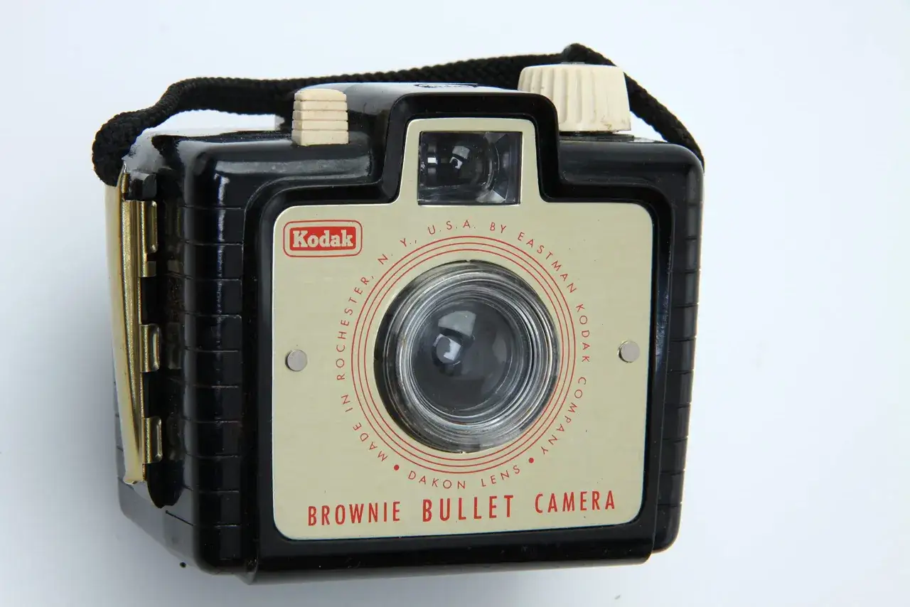 En svart Kodak Brownie Bullet Camera med en ljusbeige front och en svart rem.