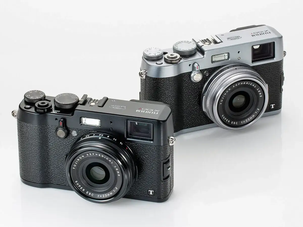 Tv&aring; Fujifilm X100T-kameror, en svart och en silverf&auml;rgad, st&aring;r sida vid sida p&aring; en vit bakgrund.