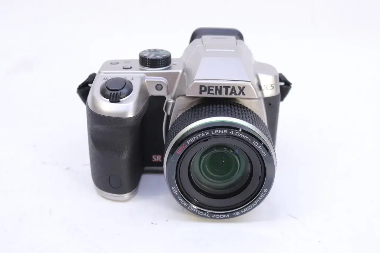 Silver Pentax X5 kamera med svart grepp och en stor lins. Perfekt för att fånga dina äventyr.