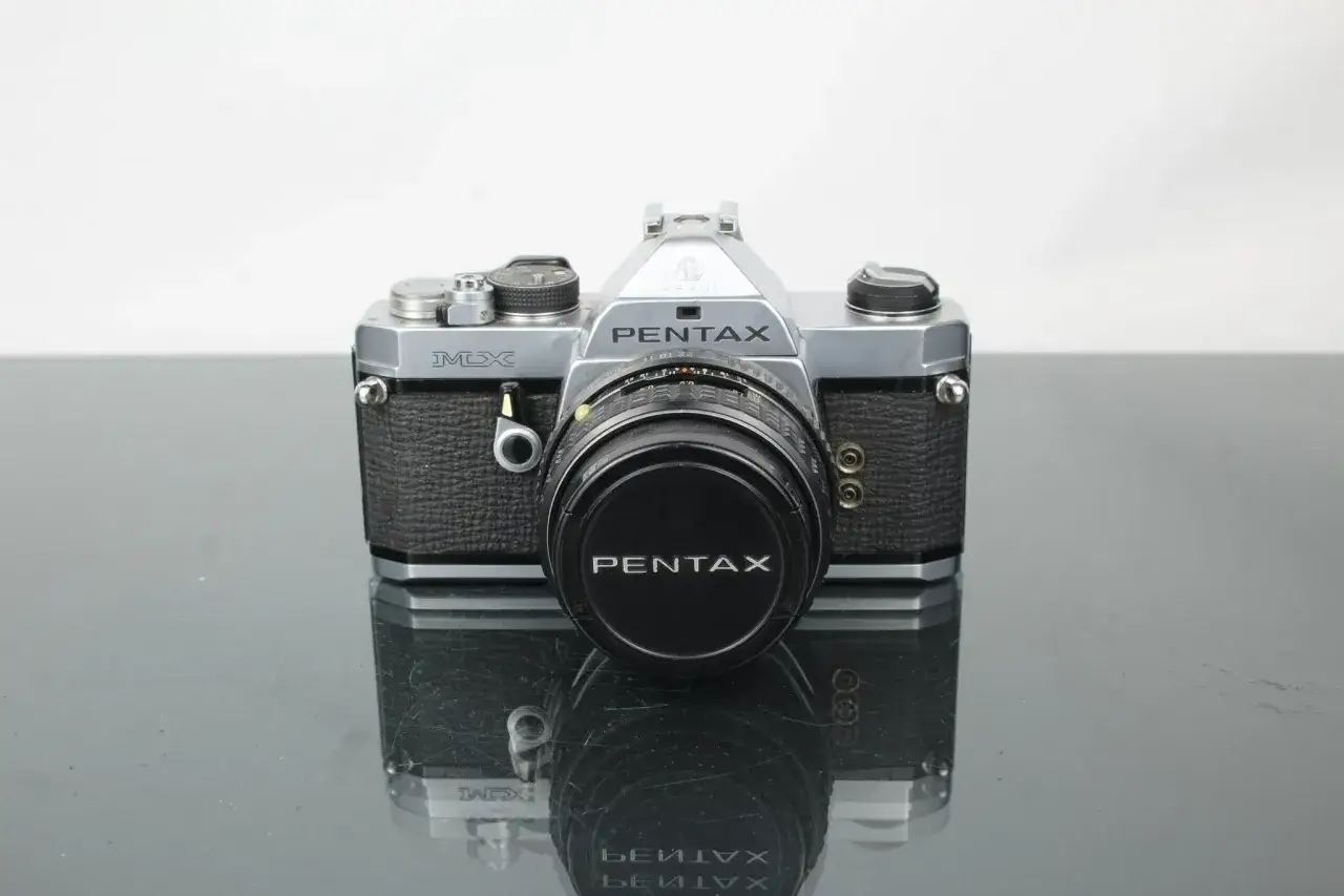 En klassisk Pentax MX-kamera med objektivlock.