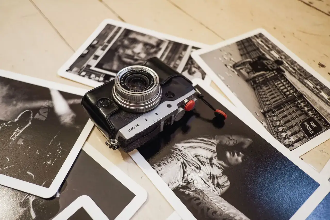 En Fujifilm X30 med l&auml;derfodral ligger bland svartvita foton.